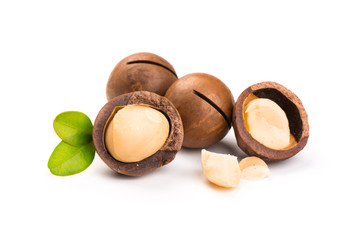 Macadamia nut with pieces and green leaves isolated on a white background