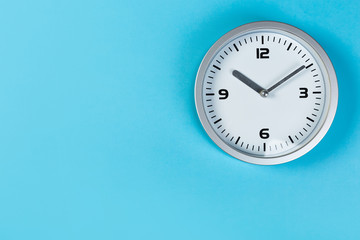 White wall clock with a yellow used hanging on the wall. Minimalist image of a wall clock on a blue background with copy space