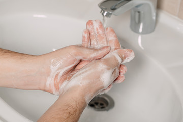 Washing hands under the water tap or faucet without soap. Hygiene concept detail. Beautiful hand and water stream in bathroom.