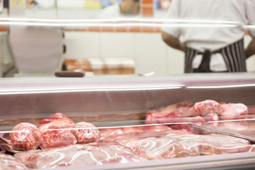 Meat in display case with man working in background