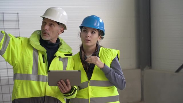 Instructor with apprentice on construction site working with tablet