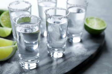 Mexican Tequila shots, lime slices and salt on grey marble table