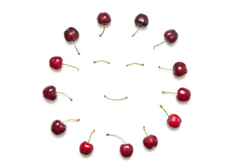 Cherries surrounding smiley face made by stems on white background