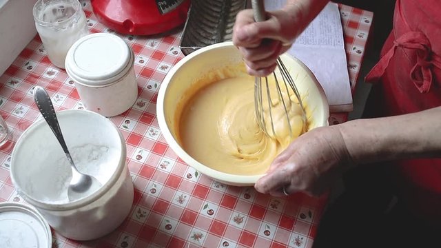 Housewife mixes the dough with a traditional kitchen utensil for pasrty. Slow motion