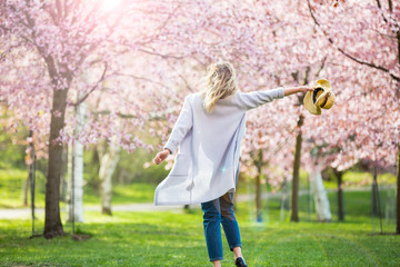 Young woman enjoying the nature in spring. Dancing, running and whirling in beautiful park with...