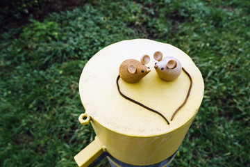 Two wooden mice couple sitting on a metal yellow round cylinder. Valentine's day concept and eco friendly. Heart shaped tails