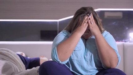 Stressful overweight woman with her husband sleeping on the bed at home. Shot in 4k resolution - Powered by Adobe