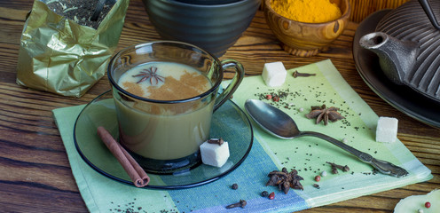 Masala tea. A Cup of traditional Indian tea masala tea with ingredients to prepare. Cinnamon, anise, sugar, black tea, pepper, cloves, turmeric on a wooden table.