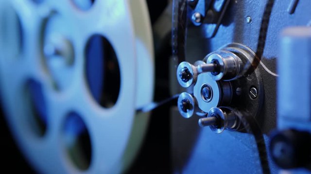 Old 8mm movie projector. The movement of the cine-film through the tape path. Clamping guide rollers and gear drums.