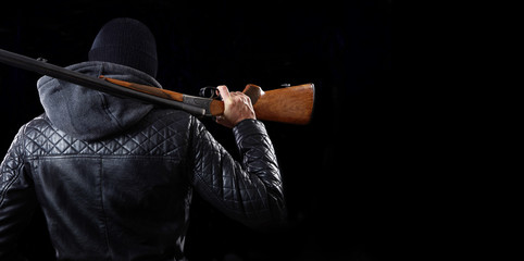 Man with shotgun on dark background.