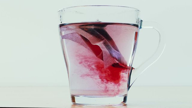 Glass cup with a bag of fruit tea pouring  boiling water