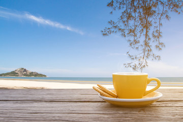 A cup of hot espresso coffee mugs placed on a wooden floor on sea view with sunlight background,coffee morning