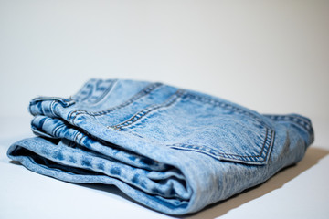 A pile of folded jeans in blue Background of clothing in indigo blue Jeans on a light background