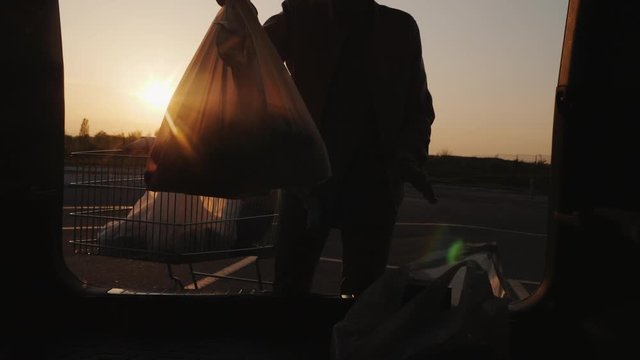 Mom and daughter put shopping from the supermarket in the trunk of the car