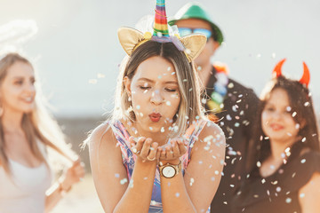 Brazilian Carnival. Young woman in costume enjoying the carnival party blowing confetti