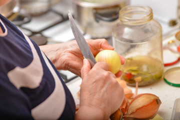 Woman peels onion with a knife from the peel, close-up