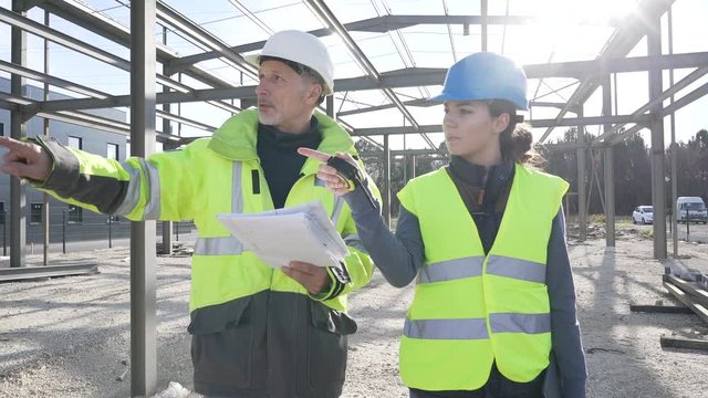Engineering instructor working on building site with apprentice