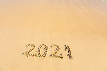 New Year 2021 is coming - inscription 2021 on a beach sand - Summer beach holiday 2021 season golden sand - old year - message handwritten - empty copy space