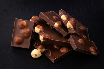 milk chocolate pieces with nuts on a dark background