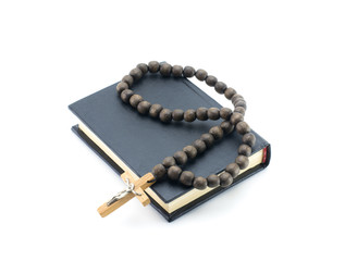 A small black book (prayer book) with wooden rosary and a cross. White background.