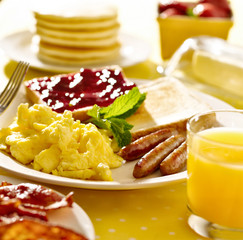 breakfast with scrambled eggs, sausage links and toast.
