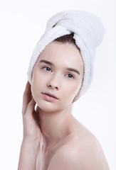 Portrait of young woman with towel wrapped around her head against white background