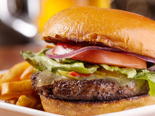 gourmet cheeseburger with mug of beer in background