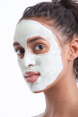Portrait of young Mixed Race woman with face pack against white background