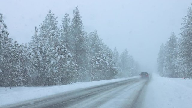 Commuters drive down a snowy country road in Spokane through a severe snowstorm. Tourists on a road trip across Washington get caught in an extreme blizzard. Cars driving in dangerous conditions.