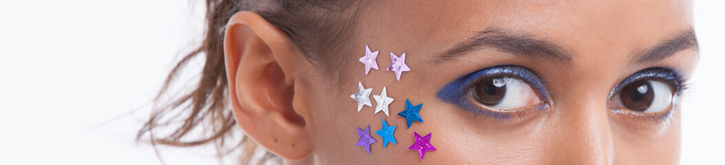Portrait of beautiful young woman with stars on her face against white background