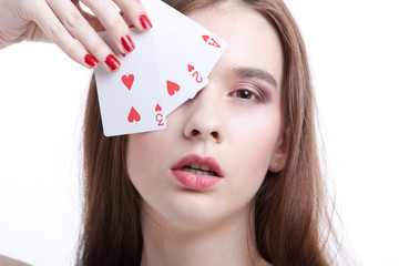 Portrait of beautiful young woman covering her eyes with playing cards against white background