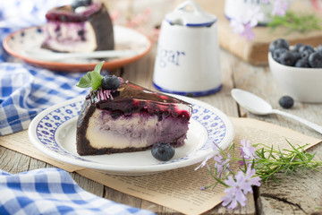 Slice of Blueberry flavour cheesecake swirled with blueberry sauce on a  biscuit crumb, bakery. Delicious slice of blueberries cheesecake with  jam and green mint.  Sweet and tasty food, coffee break 