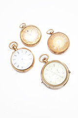 Four old-fashioned pocket watches over white background