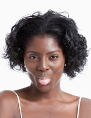 Portrait of playful young woman sticking out tongue over white background