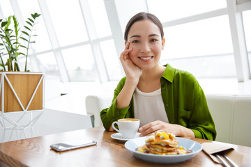 Obraz na płótnie Canvas Smiling asian woman having pancakes for breakfast