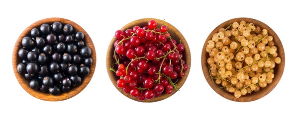 Set of different color currants isolated on white background cut out. White, red and black currant in a wooden bowl with copy space for text. Top view.