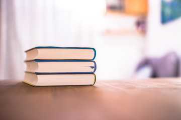 Knowledge and science concept: Stack of books lying on wooden desk, home.