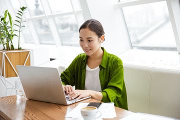 Smiling beautiful young asian woman working on laptop
