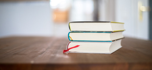 Knowledge and science concept: Stack of books lying on wooden desk, home.