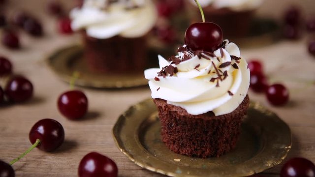 Beautiful cupcake with whipped cream cherry and chocolate on table. Homemade Party dessert. Slow motion video.
