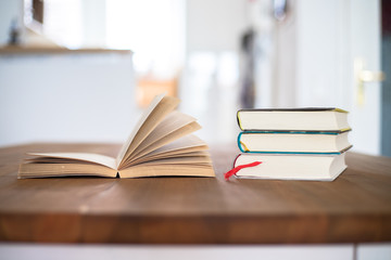 Knowledge and science concept: Stack of books lying on wooden desk, home.