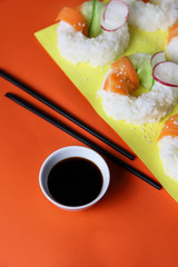 Sushi donuts with raw carrots, cucumber and radish on yellow orange paper background. Contemporary food concept, trendy Asian dinner for vegan or vegetarian, close up, top view