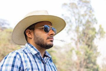 Young cowboy with dark glasses and looking at the horizon