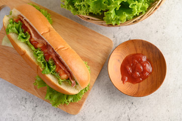 Hotdog with lettuce and tomato sauce on Wood cutting board wood cutting board
