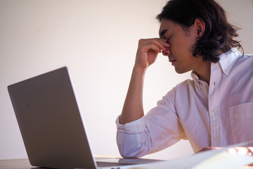 Asian businessmen are tired and have eye strain after sitting for a long time.