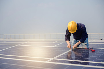 Electrician working on measurement Voltage at solar cell on building roof ,  Renewable energy Concept.