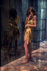 Glamorous girl in a silk robe in a dark interior of mirrors.