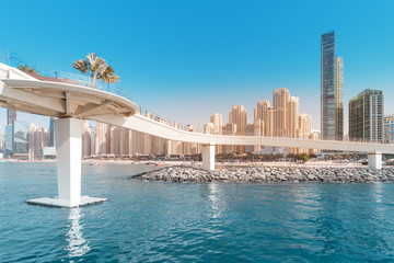 Fototapeta na wymiar Pedestrian Footbridge at the Dubai Marina harbor with various residential buildings at the background