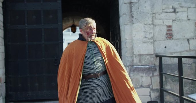 Old, wounded hetman walks on fortress yard and looks around