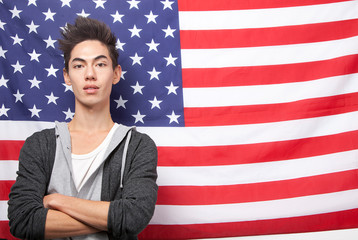 Portrait of young mixed race man with arms crossed standing against American flag